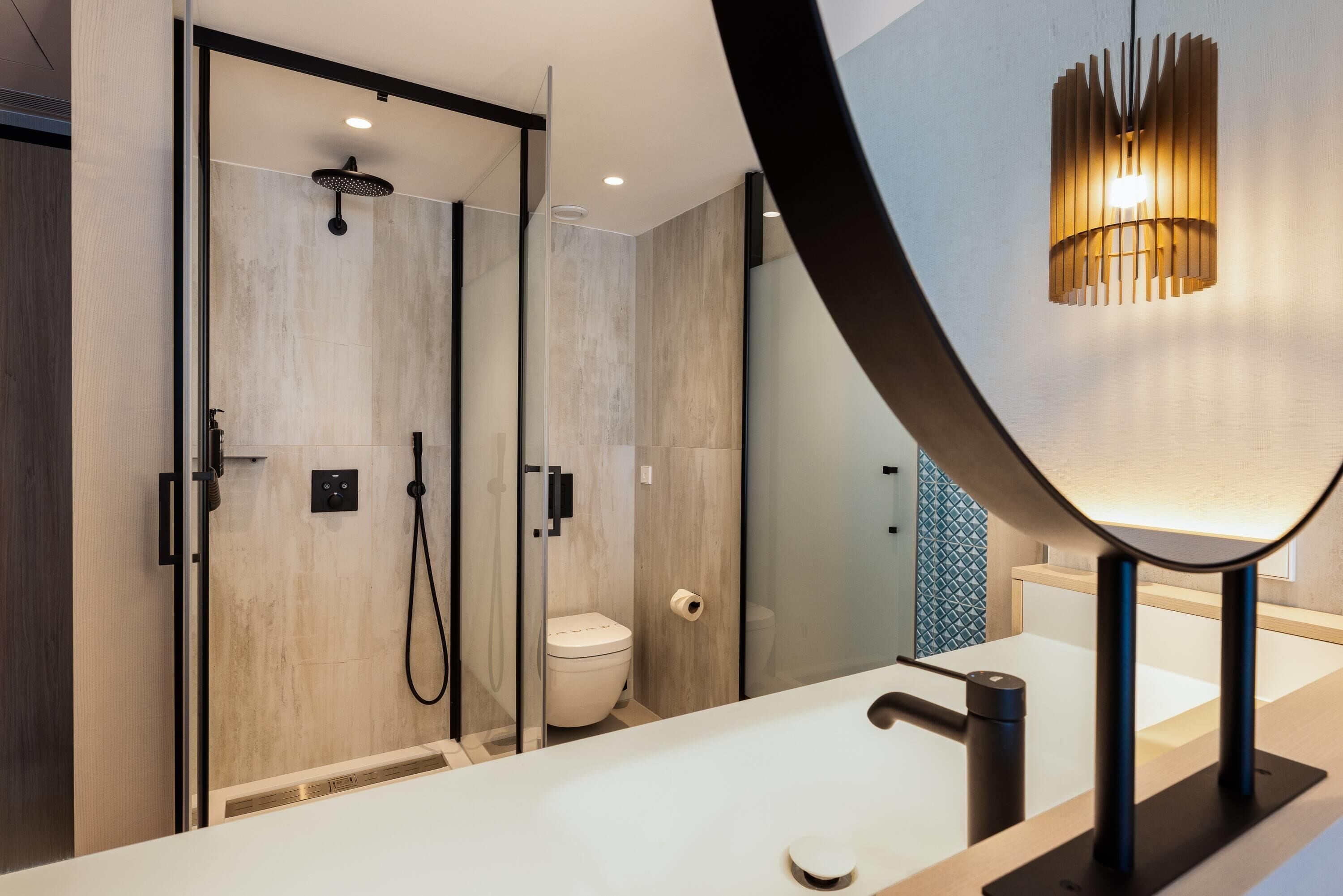 A modern bathroom with a glass shower enclosure, a toilet, and a vanity with a mirror.