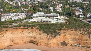 Un hotel frente al mar con varias construcciones, una playa y acantilados.