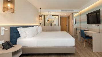 Ein modernes Hotelzimmer mit einem großen Bett, einem Nachttisch mit Telefon, einem Schreibtisch mit Stuhl, einem Fernseher und einem Spiegel.