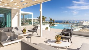 Una terraza en la azotea con mobiliario exterior, piscina y vista al océano.