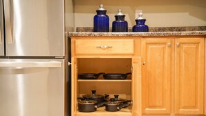 Una cucina con frigorifero in acciaio inox, mobili in legno, piano di lavoro in granito e barattoli azzurri.