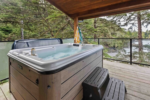 Un jacuzzi en una terraza de madera con vistas a un lago y árboles.