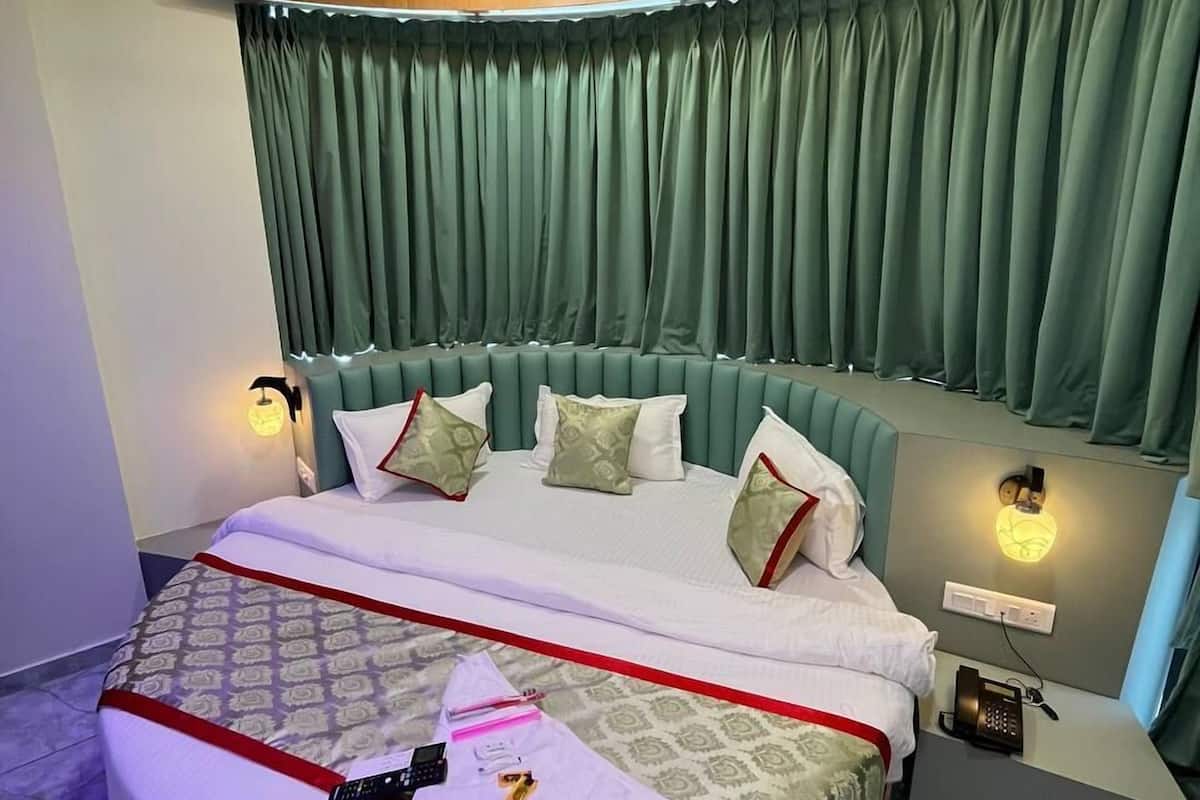 A modern bedroom with a curved bed, green curtains, and a ceiling fan.