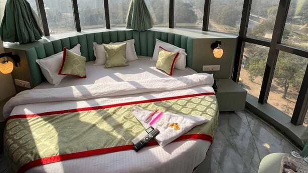 Une chambre d’hôtel située dans un immeuble de grande hauteur, avec un lit aux courbes élégantes, de grandes fenêtres et une vue sur la ville.