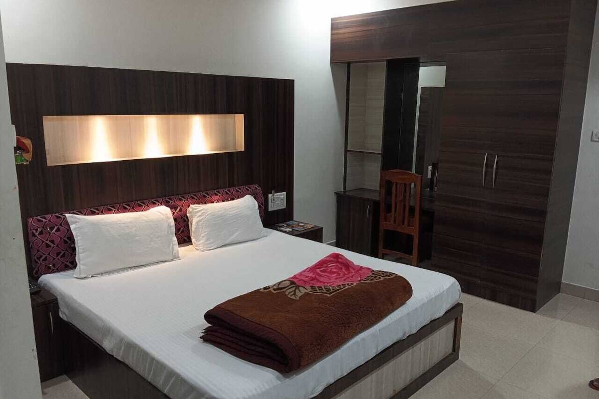 Ein modernes Schlafzimmer mit einem großen Bett, einem dunklen Holz-Kopfstück und einem integrierten Kleiderschrank.