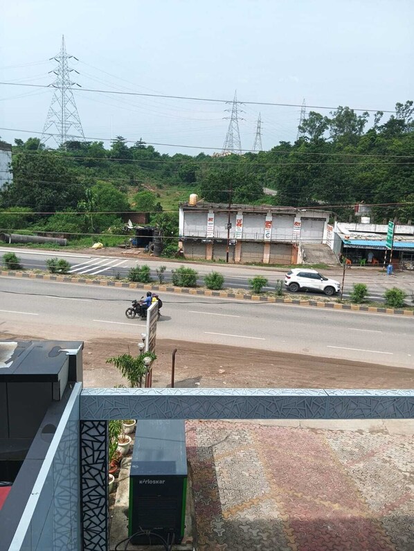 A street view with a building that has multiple signs, a parked white car, and a motorcycle. There are power lines and trees in the background.