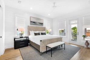 Une chambre moderne avec un grand lit, des tables de chevet, un banc et une vue sur l’extérieur.