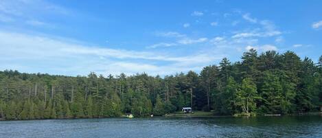 A lake with a forested shore, a small dock, and a cabin.
