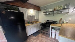 Une cuisine avec des armoires blanches, un réfrigérateur noir, une cuisinière et un évier.
