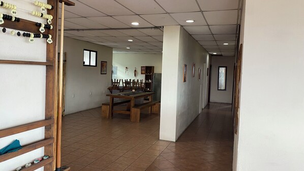 A hallway with a dining area featuring a wooden table and chairs, a refrigerator, and a window. - Casa Lucia Oaxaca (Oaxaca)