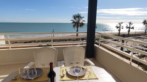 A table set for two with plates, cutlery, and a bottle of wine on a balcony overlooking a beach. - Apartamento Picasso 3 Inmomart (Peñiscola)