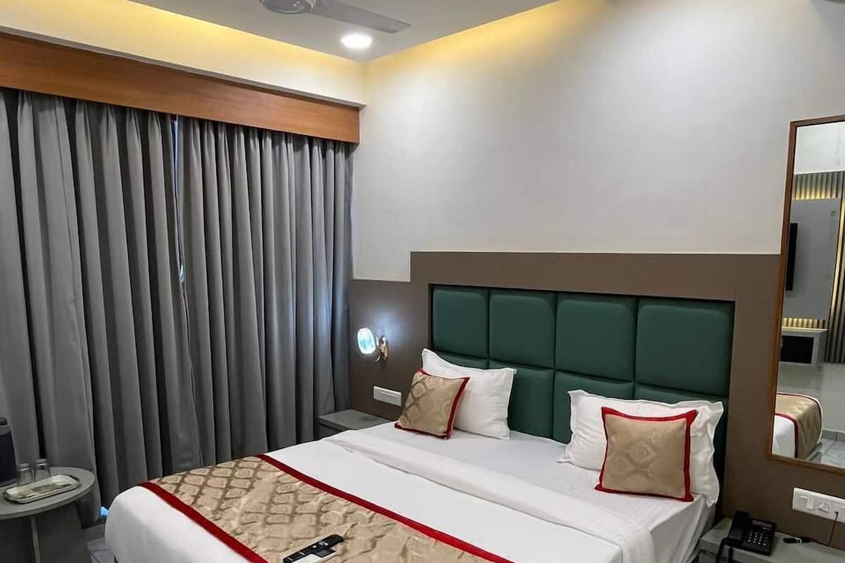 Ein modernes Hotelzimmer mit einem großen Bett, einem Nachttisch, einem Spiegel und einem Deckenventilator.