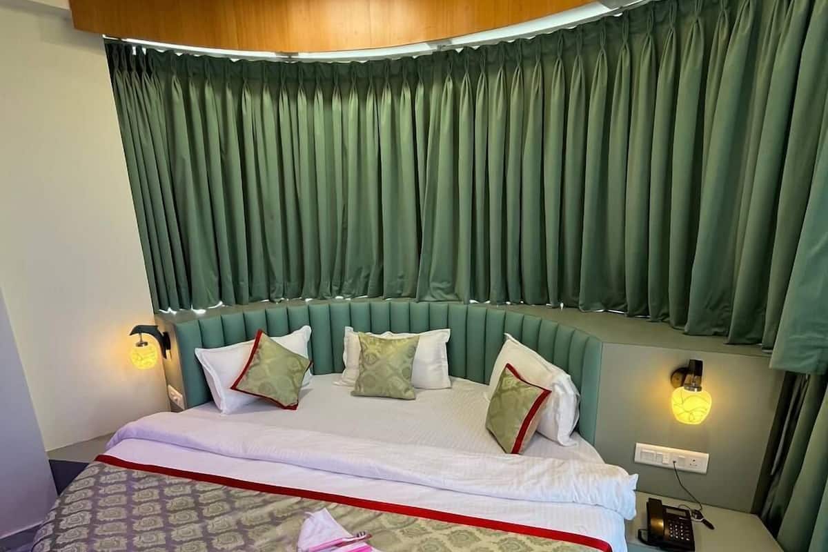 Ein rundes Bett mit Kopfteil, Nachttisch und Beistelltisch mit Telefon und Lampe.