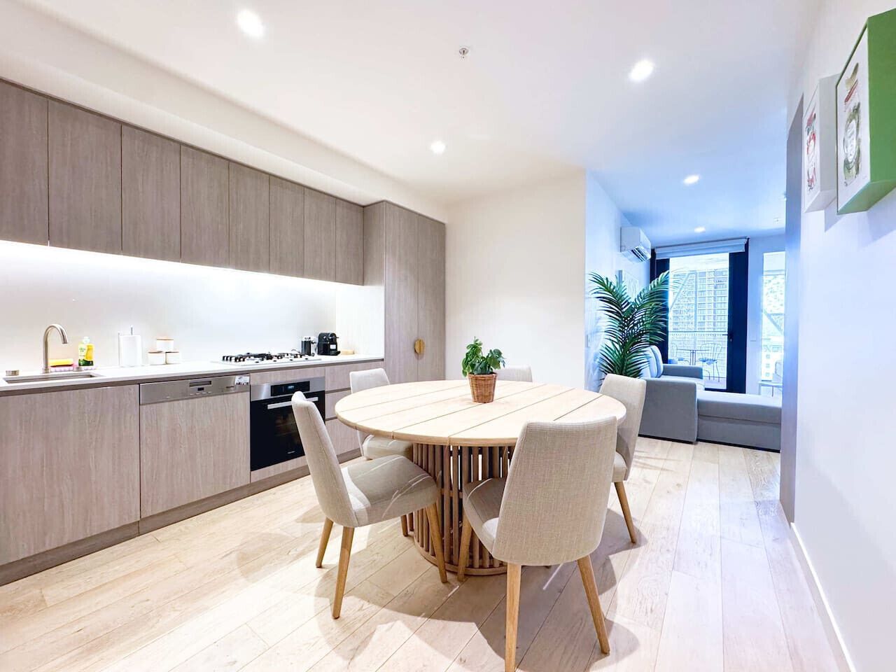 Una cocina moderna con comedor, armarios de madera y una mesa redonda con sillas.