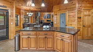 A wooden cabin interior with a large kitchen island, wooden walls, and pendant lighting. - You have to see Red Bird Lodge (SEVIERVILLE)
