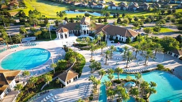 Een resort met meerdere zwembaden, palmbomen en een golfbaan op de achtergrond.
