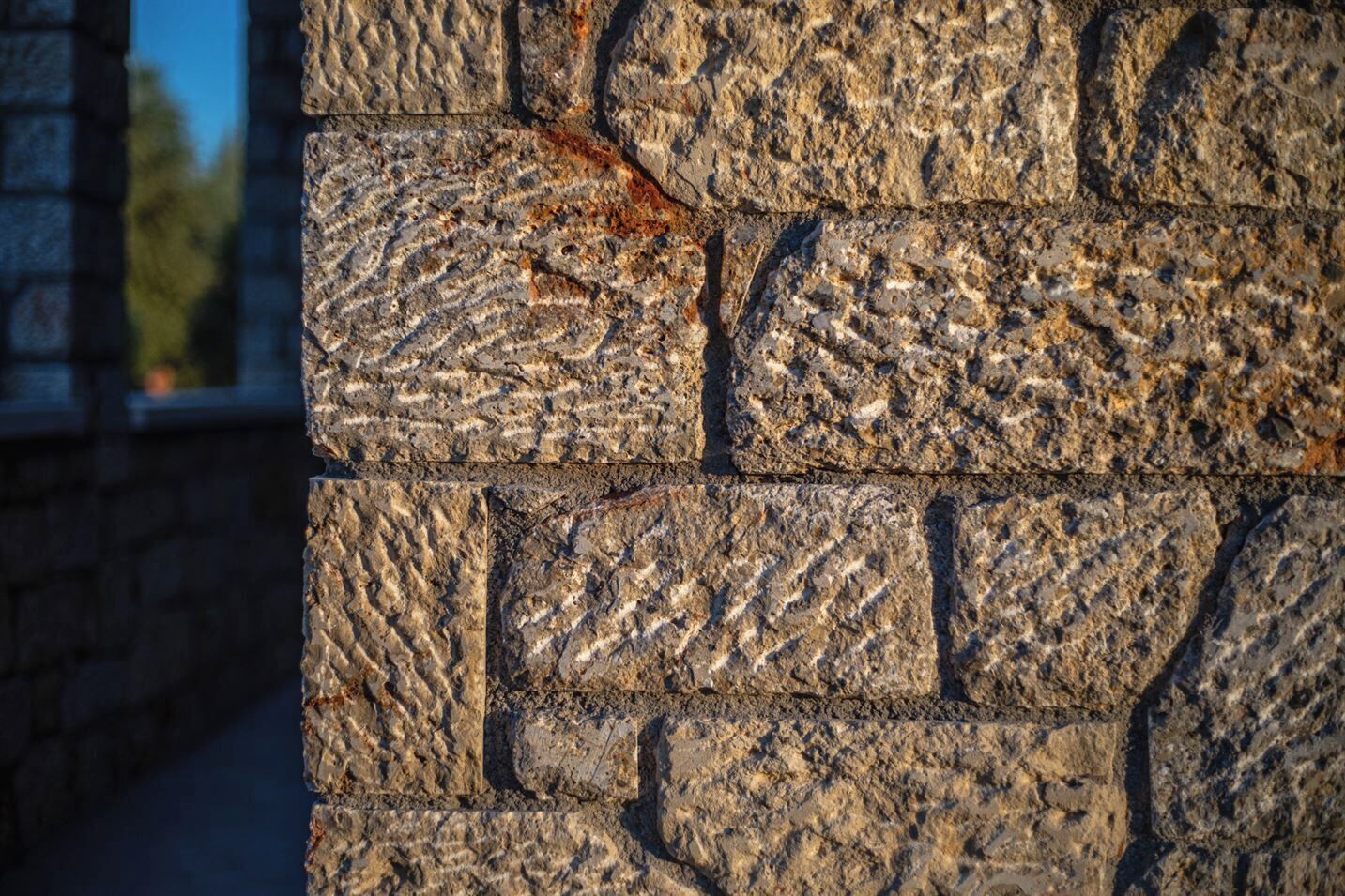 Um close-up de uma parede de pedra com superfície texturizada e juntas de argamassa visíveis.