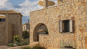 A stone building with a courtyard, featuring an arched window and a small balcony. - Dream Villas (West Mani)