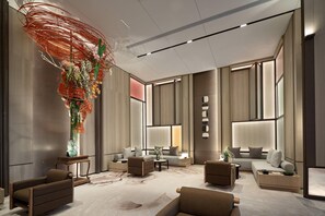A modern hotel lobby with a sofa set, a coffee table, and a decorative plant arrangement. - Ramada by Wyndham Foshan Danzao (Foshan)