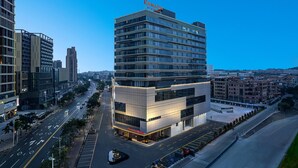 A modern hotel with a prominent 'RAMADA' sign, featuring a multi-story structure with large windows and a well-lit facade. - Ramada by Wyndham Foshan Danzao (Foshan)