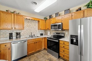 Una cocina moderna con armarios de madera, electrodomésticos de acero inoxidable y lavavajillas integrado.
