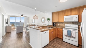 A modern kitchen with wooden cabinets, a white dishwasher, and a built-in oven. - Open Oct 25–Nov 2! Beautiful Condo Near Pier Park! (Panama City Beach)