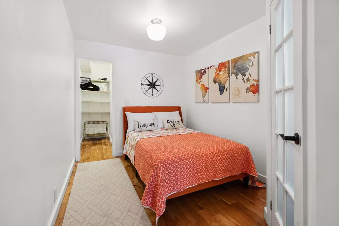 Um quarto com uma cama, um ornamento de bússola na parede, e um mapa-múndi.