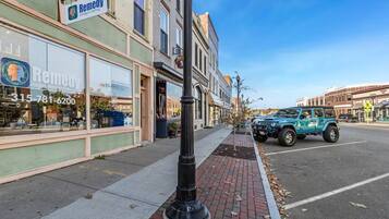 A street view with a building labeled 'Remedy' and a parked blue Jeep on the sidewalk.