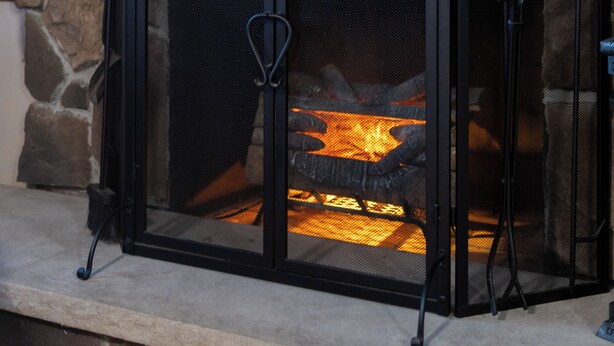 A stone fireplace with a metal screen and a decorative horseshoe. - SOFIMA-Cozy and Charming 2-bedroom apartment! (Woburn)