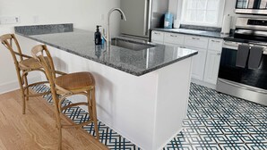 A modern kitchen with a central island, stainless steel appliances, and a patterned floor.
