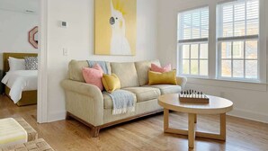 A living room with a beige sofa, colorful cushions, a round coffee table, and a chessboard.