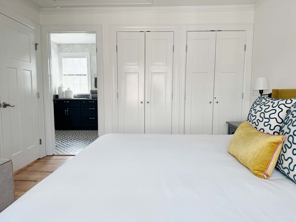 A bedroom with a large bed, white walls, and a wardrobe with two doors.