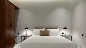 A bedroom with a large bed, two bedside tables with lamps, a wooden wardrobe, and a white ceiling. - M-Residence by Dayf Self-Service Apart. (Jeddah)