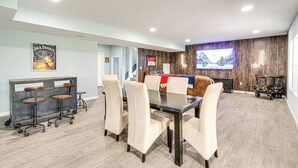 Una sala de estar moderna con comedor, que incluye un televisor grande, un sofá y una mesa de centro.