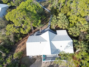 A large, modern house with a sloped roof, surrounded by dense greenery and trees. - Canal Front Pet Friendly Boat Dock St George Island-Beach access (Eastpoint)