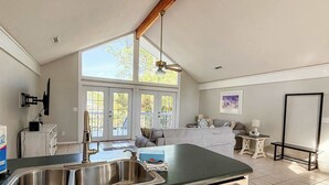 Uma cozinha com uma pia dupla, uma área de refeições com mesa e cadeiras, e uma janela grande com vista para o exterior.