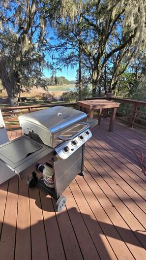 A portable grill on a wooden deck with a view of trees and a lake. - Minutes from Rainbow Springs, 2/2, lake front home! Beautiful back porch! (Dunnellon)