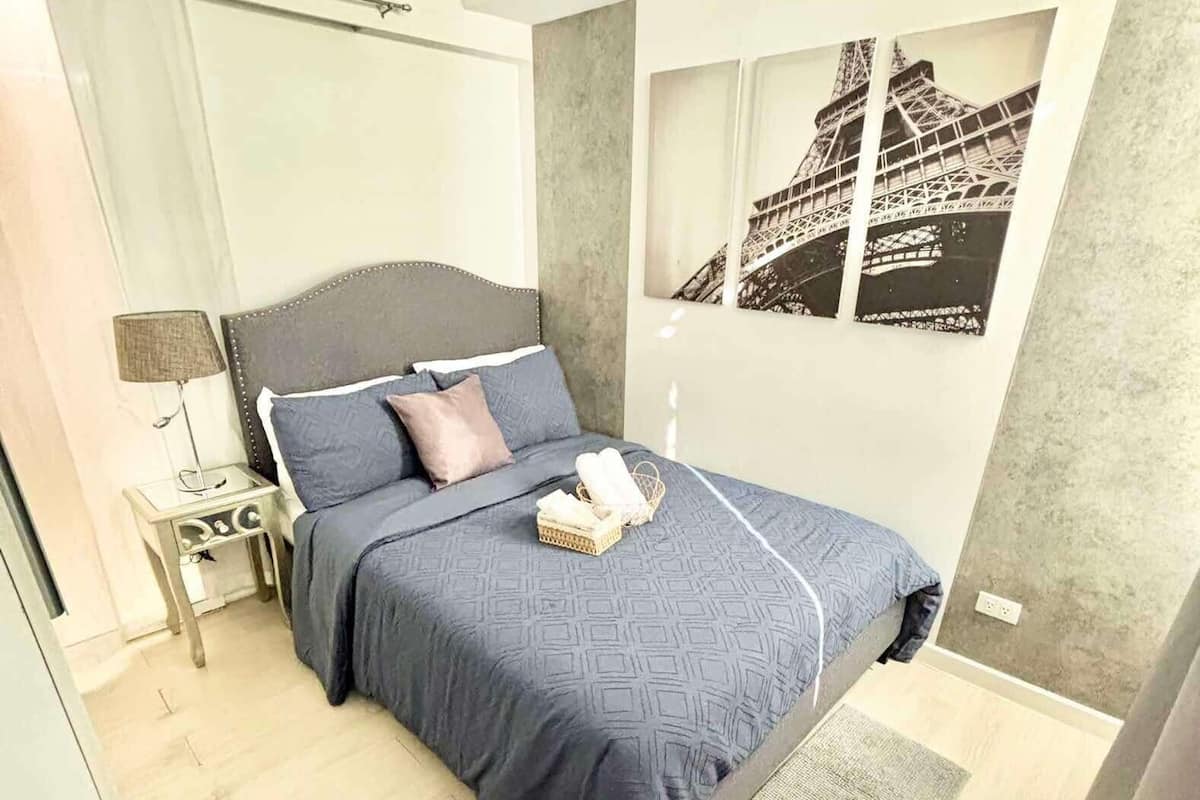 Une chambre à coucher moderne, avec un lit, une table de chevet, une lampe et une fenêtre donnant sur un pont.
