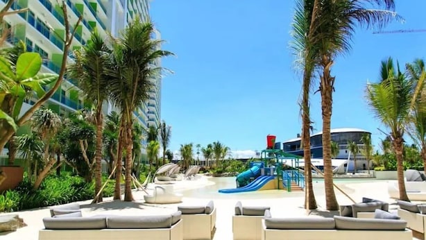 A resort pool area with lounge chairs and a water slide.