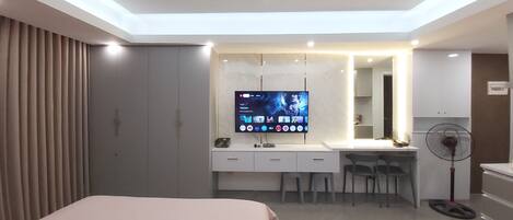 Una habitación de hotel moderna con cama, escritorio, televisión y ventilador.