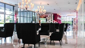A modern hotel lobby with black armchairs, a round table, and a chandelier.