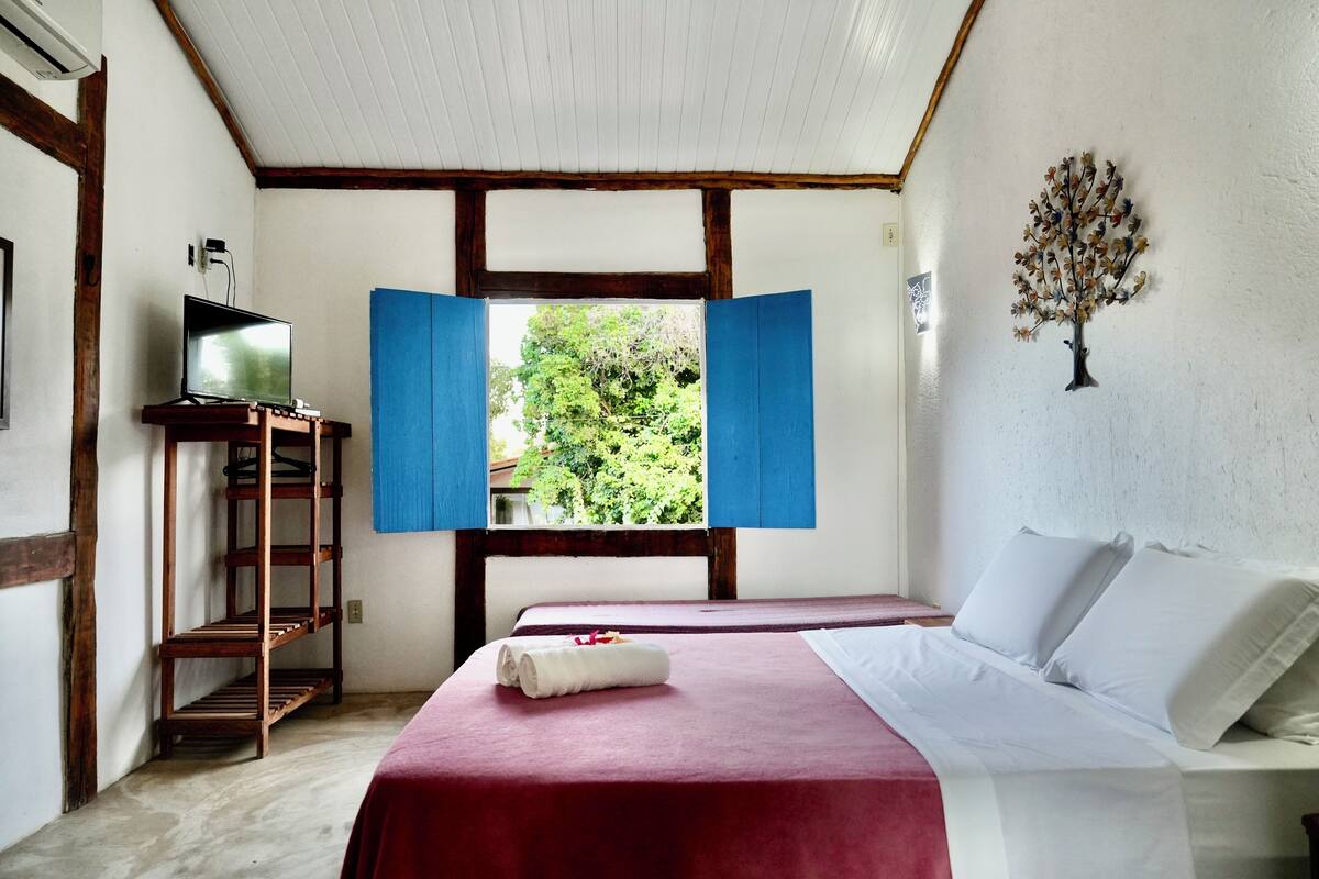 Ein Zimmer mit einem Bett, einem Fernseher auf einem Regal und einem Fenster mit blauen Fensterläden.