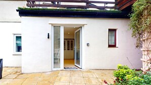 A modern house with a white exterior, a glass door entrance, and a tiled patio.