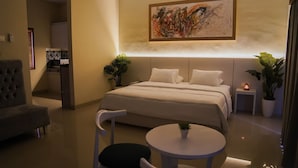 Un dormitorio moderno con una cama grande, mesitas de noche, un escritorio y sillas.