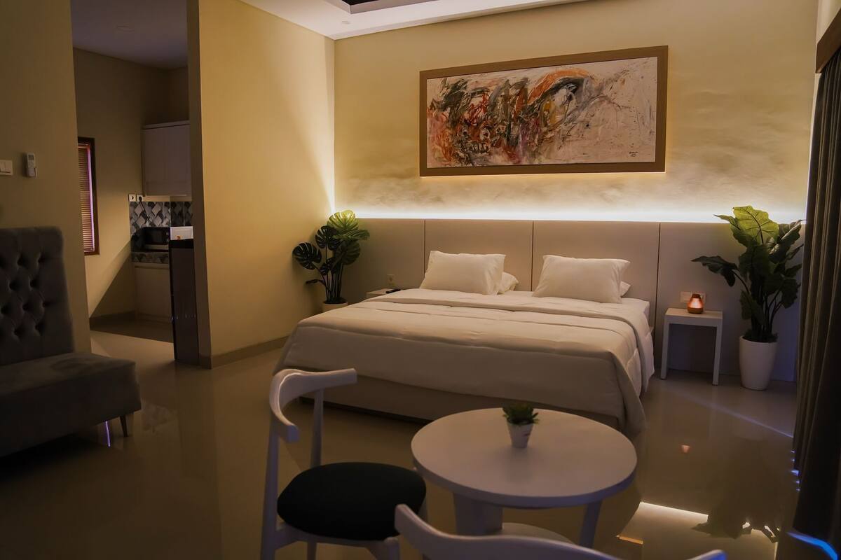Une chambre moderne avec un grand lit, des tables de chevet, un bureau et des chaises.