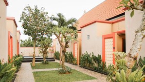 Un patio con un sendero empedrado, palmeras y un edificio con puertas rojas.
