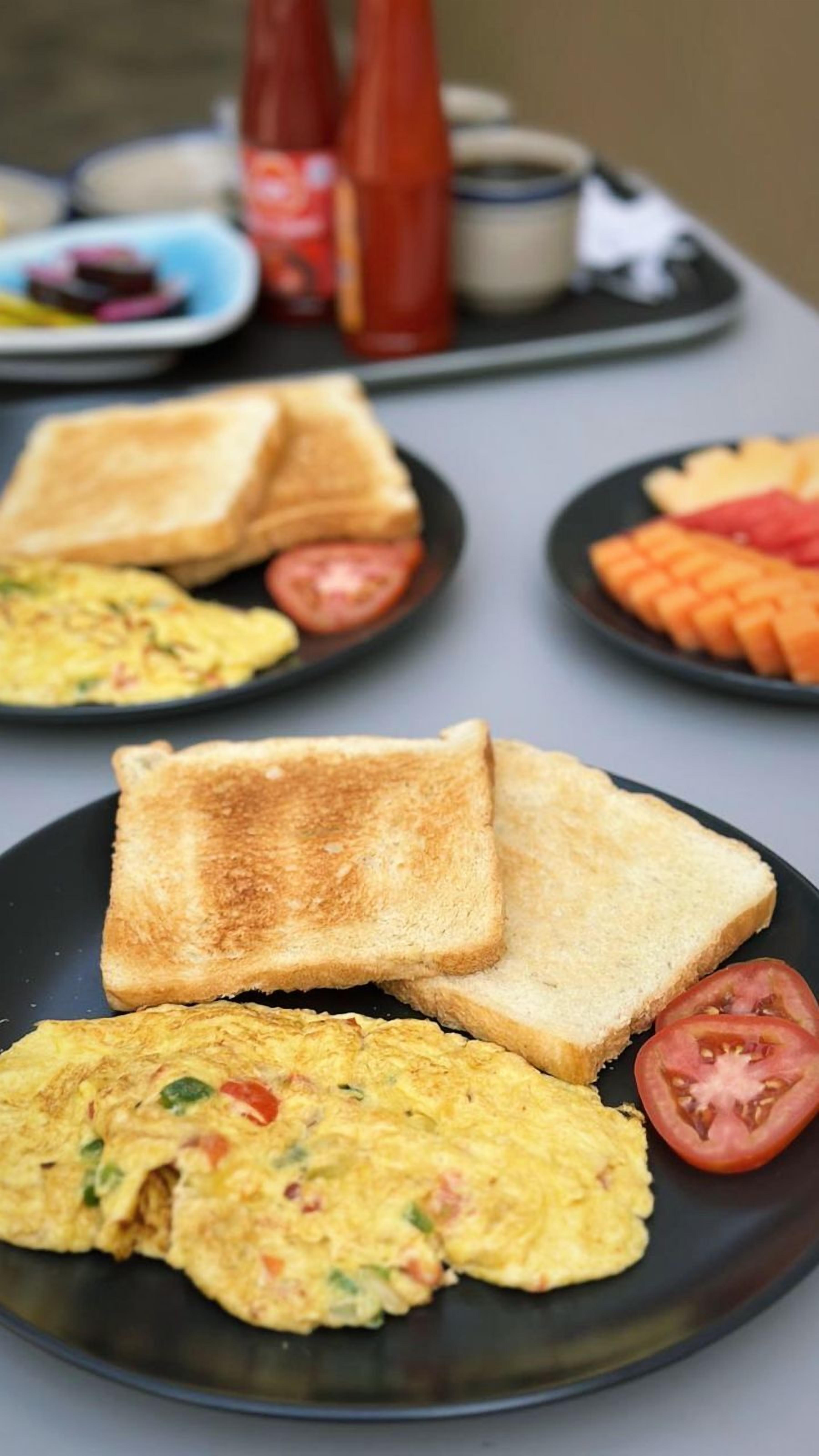 Ein Frühstücksteller mit Toast, Rührei und Tomatenscheiben.