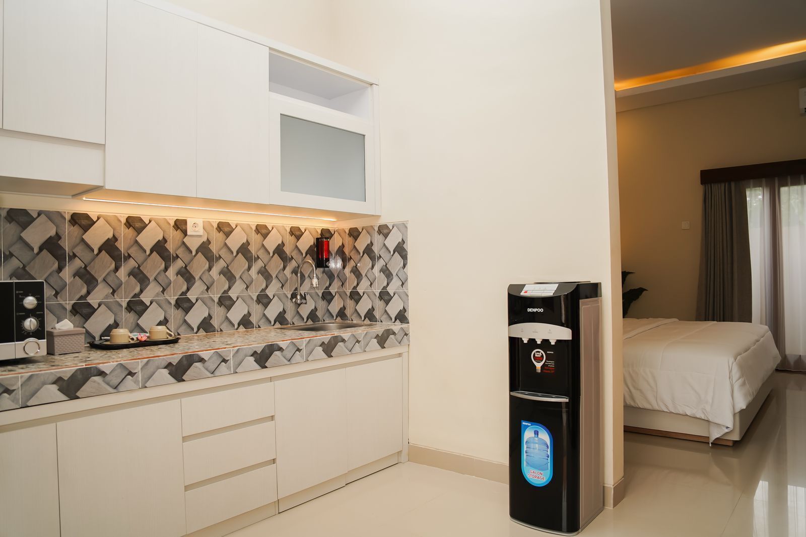 A modern kitchen with a water dispenser, a microwave, and a tray with cups and a tissue.