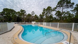 A swimming pool with a curved edge, surrounded by a white fence, and a paved walkway. - New Listing! 30A Condo Close to Beach, Shopping and Dining! (Santa Rosa Beach)