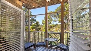 A covered outdoor area with a table and chairs, a view of trees, and a wooden ceiling. - New Listing! 30A Condo Close to Beach, Shopping and Dining! (Santa Rosa Beach)